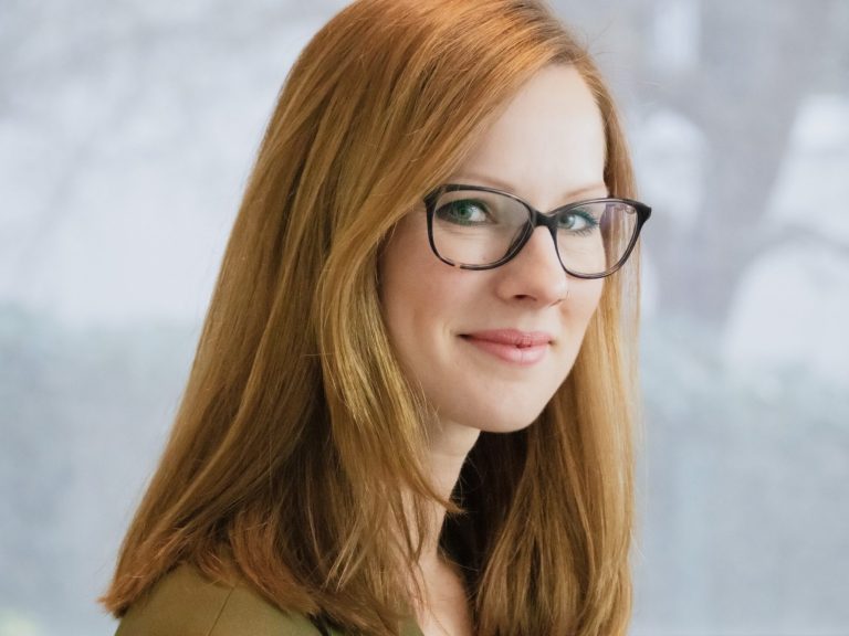 Profilbild Junge Frau mit blonden Haaren, Brille und einem freundlichen Lächeln.