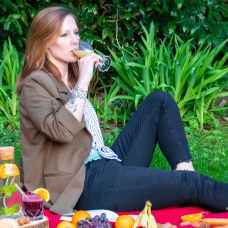 Gesunde Ernährung Frau mit langen, braunen Haaren hält zwei Cocktails in den Händen, lächelnd.