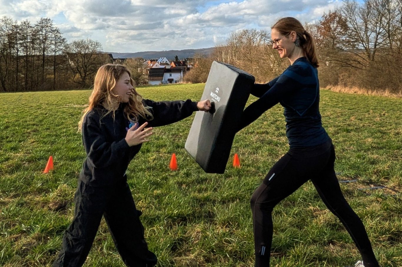 Training Zwei Frauen trainieren im Freien, eine hält ein Trainingsschild, die andere übt einen Schlag.