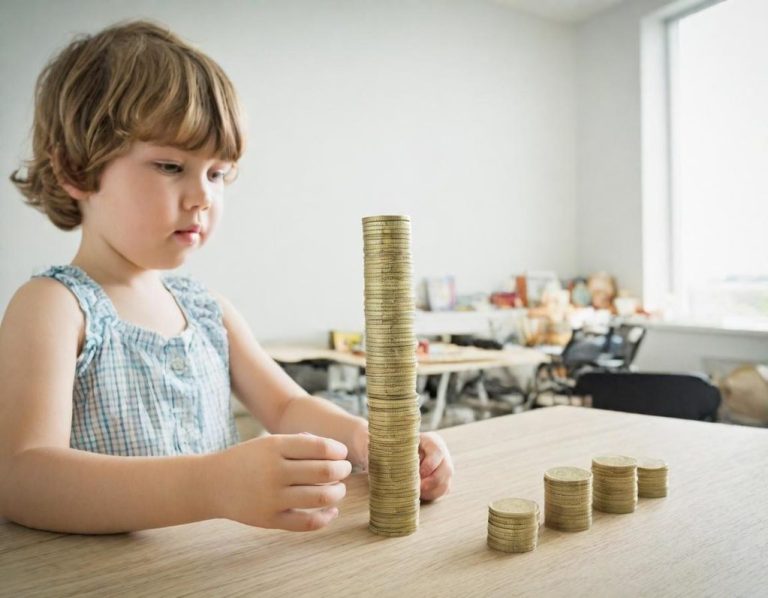 Ein Kind baut einen hohen Turm aus Münzen auf einem Tisch.